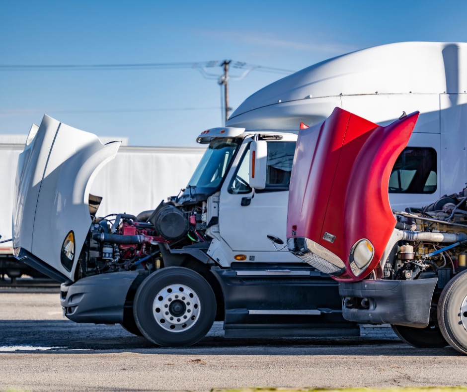 White semi-truck with its hood raised, exposing the engine in a truck yard